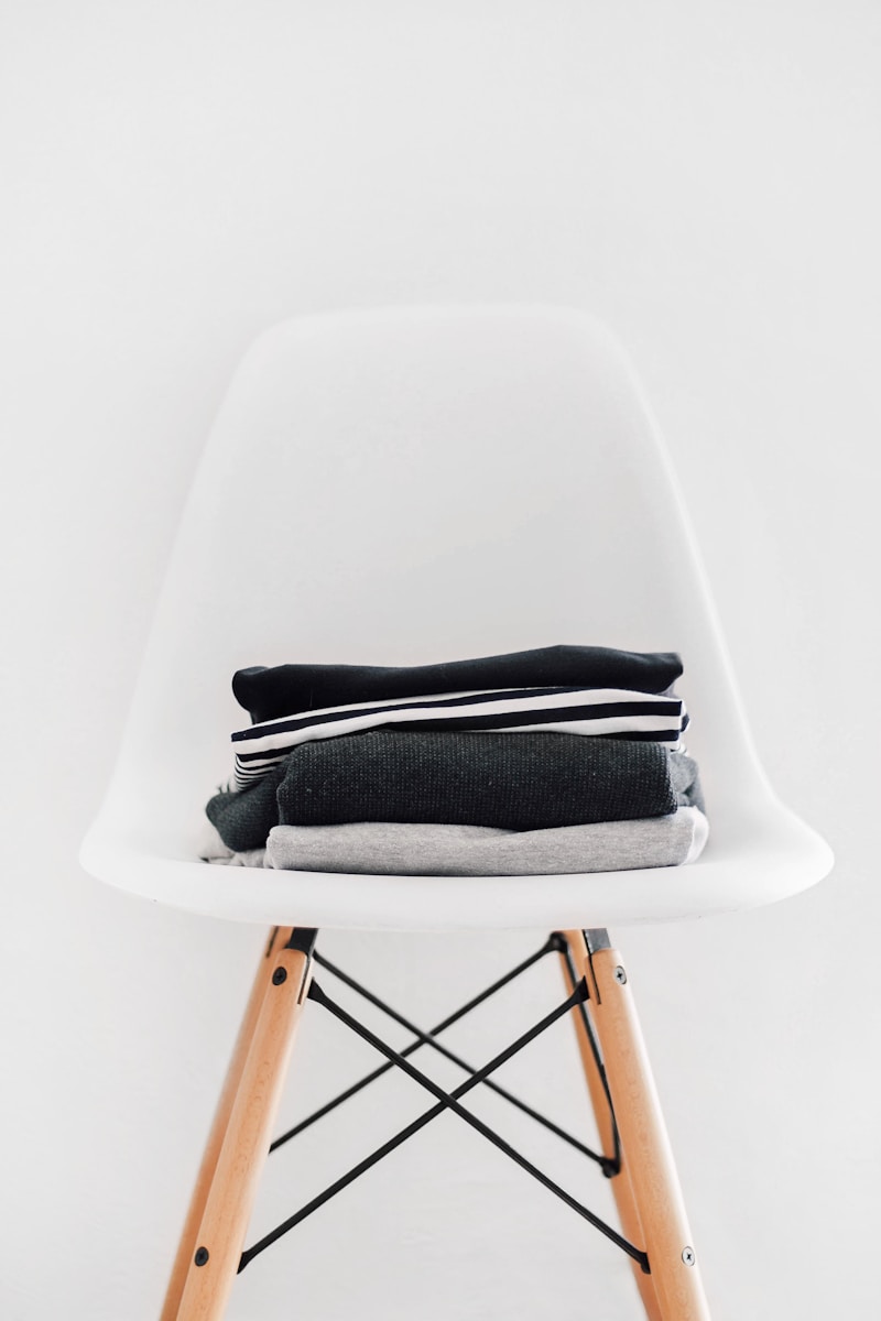 pile of black, white, and gray cloths on white padded chair. items separated during personal styling session, personal styling